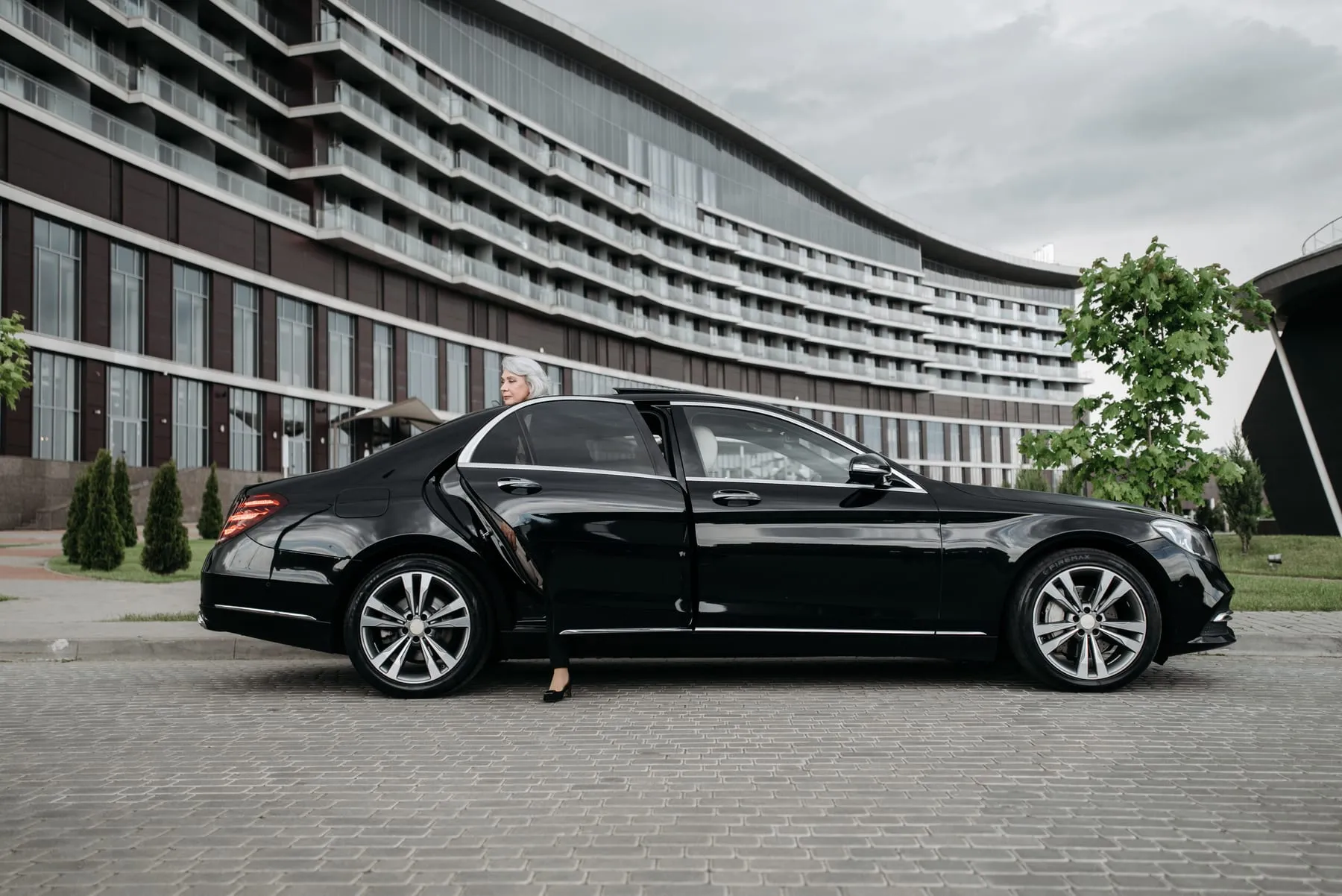 A passenger stepping into a black Mercedes-Benz saloon at the kerbside — Black Car Service Frankfurt