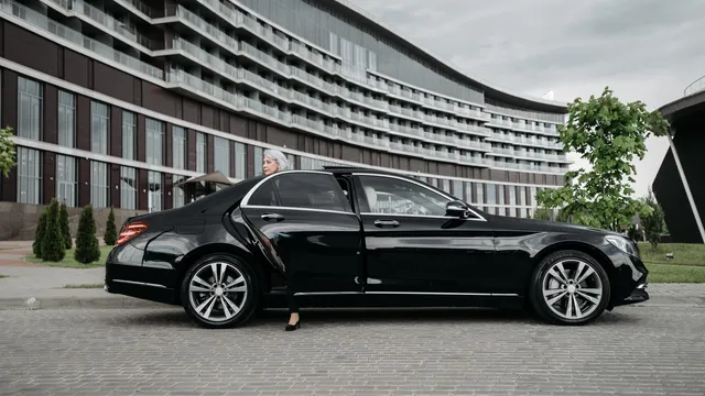 A passenger stepping into a black Mercedes-Benz saloon at the kerbside — Black Car Service Essen – Düsseldorf Airport