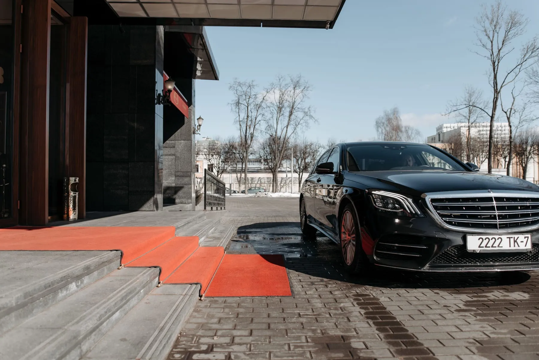 A dark saloon parked at the entrance of a corporate building — CEO & Board Chauffeur Service Frankfurt