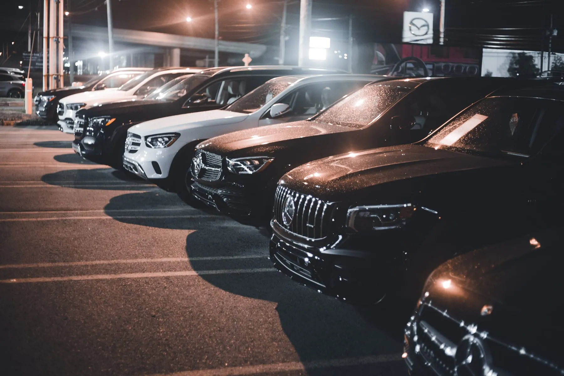 A line of black saloons parked under lights at night — Private Chauffeur & Airport Transfers