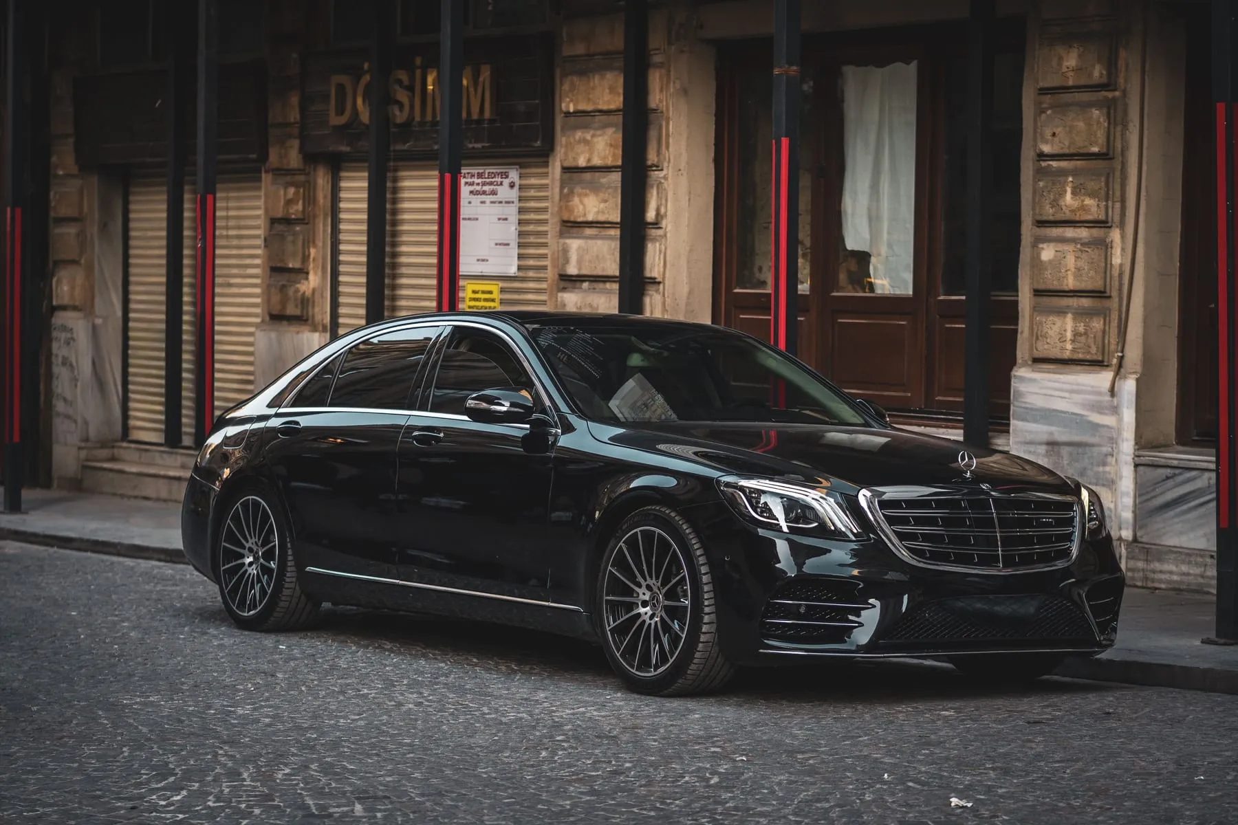 A black saloon parked on a cobbled street in a European city — Hourly Chauffeur Service Frankfurt — Driver on Standby