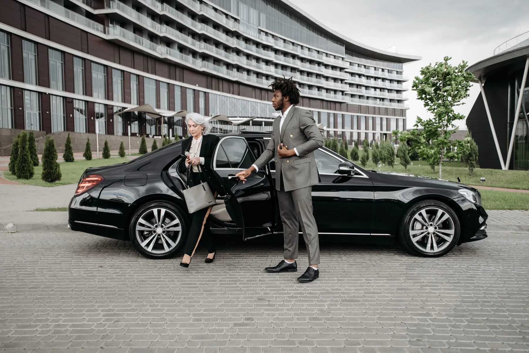 A chauffeur holding the rear door of a black saloon at a hotel entrance — Limousine Service Frankfurt
