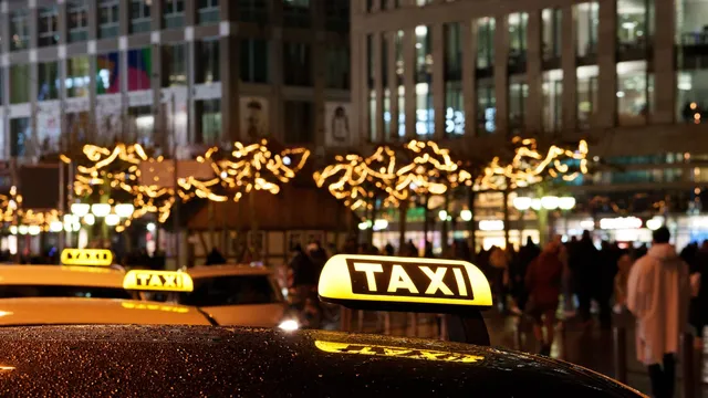 Illuminated German taxi roof signs on a wet city street at night — Taxi Alternative Essen – Düsseldorf Airport